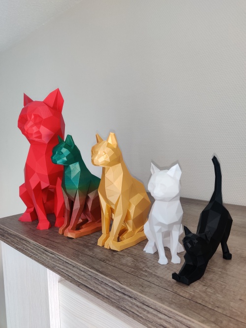Figurines de chats, pour la SPA de la Mayenne, en ligne posées sur un meuble. La plus grande est rouge, ensuite une multi couleurs puis une or, une blanche et pour finir une en couleur noire.