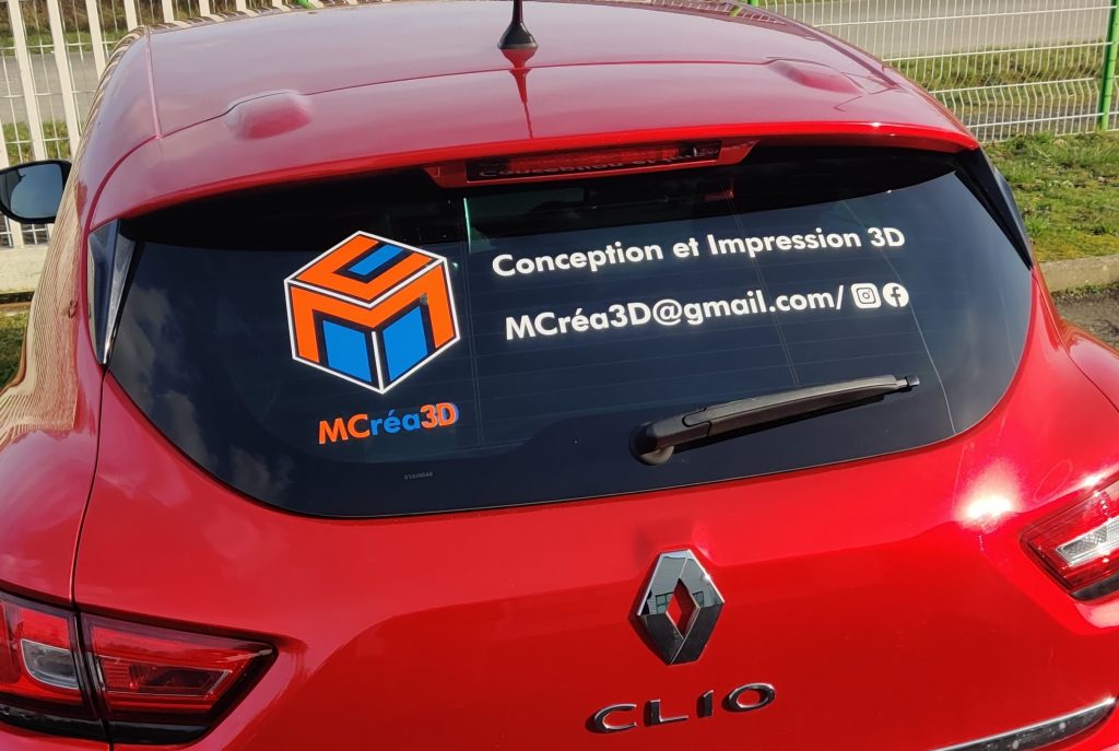 Service Mcréa3D qui est la livraison avec sa voiture qui est rouge et reconnaissable avec les stickers collés sur le pare brise arrière. 